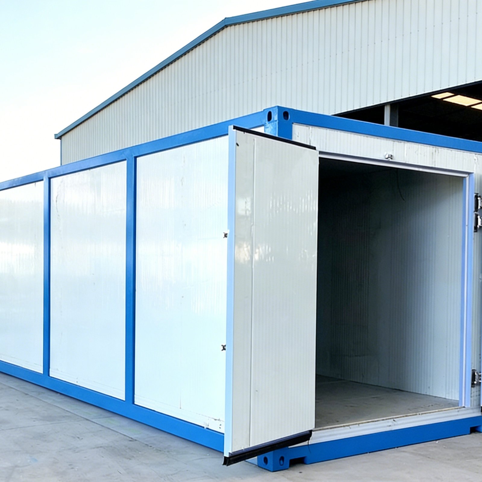 Cámara de enfriamiento por vacío con puerta abierta, sitio de instalación exterior, edificio de fábrica en el fondo